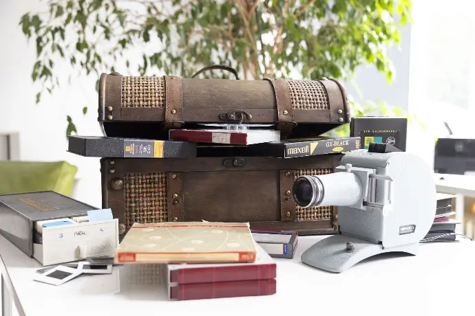 Eine Schatzkiste mit diversen analogen Medien wie Super-8-Filmrollen, Videokassetten, VHS, miniDV Kassetten, Tonbänder sowie ein Diaprojektor