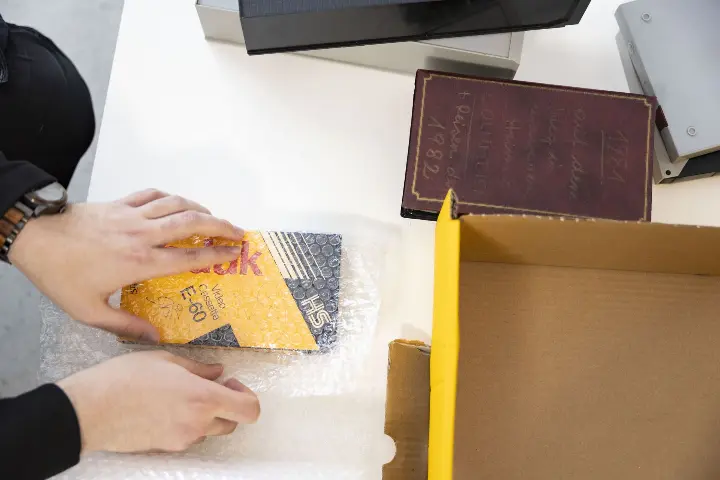 Person wickelt eine alte VHS - Kassette in Luftpolsterfolie ein – Schritt zur sicheren Verpackung vor dem Versand an FORVIDEO VHS - Kassette _ Luftpolsterfolie