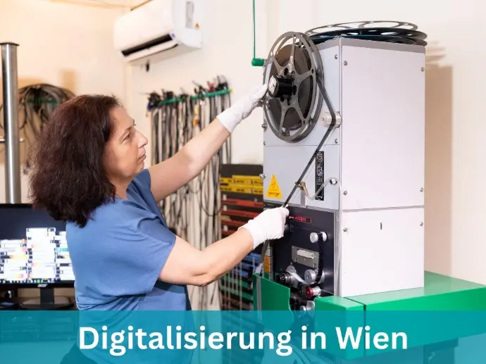 Filmdigitalisierungsexpertin steht an einem 16mm Filmscanner mit einem Schmalspurfilm in der Hand