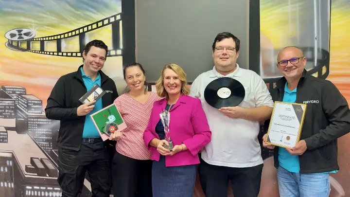 das Forvideo Team bestehend aus 3 Männern und 2 Frauen präsentieren als Gruppe den HIPE Award Pokal zusammen mit analogen Medien, die digitalisiert werden.